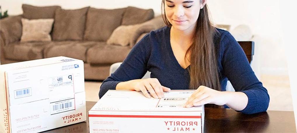 Woman attaching a shipping label to a Priority Mail box.